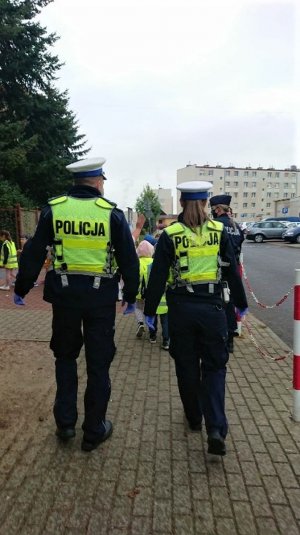 policjant i policjantka idą za dziećmi