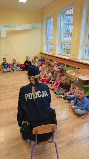 policjantka siedzi na krześle i rozmawia z dziećmi w przedszkolu