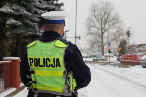 policjant ruchu drogowego stoi przy ośnieżonej jezdni