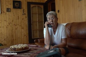 starsza kobieta w okularach trzyma słuchawkę telefonu