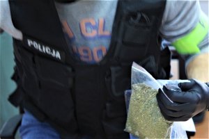 policjant trzyma woreczek z zabezpieczonymi narkotykami