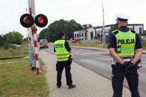 policjant i funkcjonariusz SOK przed szlabanem kolejowym
