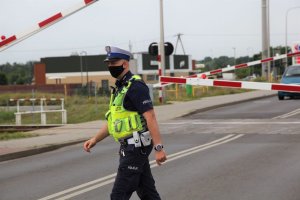 policjant przed szlabanem kolejowym