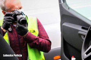 policjant w kamizelce fotografuje samochód