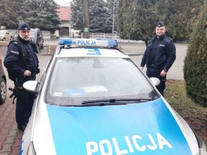 policjanci stoją przy radiowozie