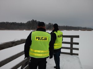 policjanci stoją przed zamarzniętym jeziorem