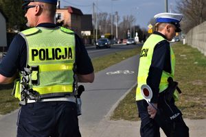 policjant i policjantka w odblaskowych kamizelkach na drodze