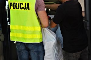 policjant w kamizelce odblaskowej stoi przy worku