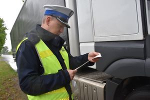 policjant sprawdza wydruk z tachografu