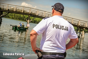 policjant stoi na brzegu jeziora