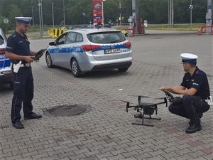 policjanci ruchu drogowego z dronem przy radiowozie