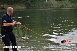 policjant wyciąga z wody osobę