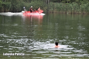 osoba w wodzie , w oddali łódka straży pożarnej