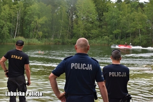 policjanci i strażak patrzą w stronę zbiornika wodnego