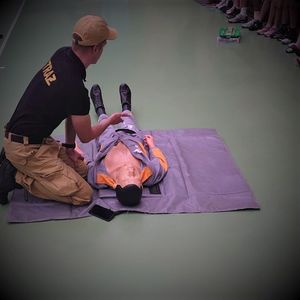 strażak pokazuje na manekinie jak udzielić pierwszej pomocy