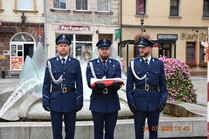 policjanci w mundurze trzymają flagę