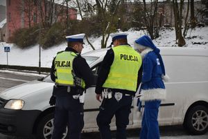 policjanci w kamizelkach przy aucie razem z polikołajem