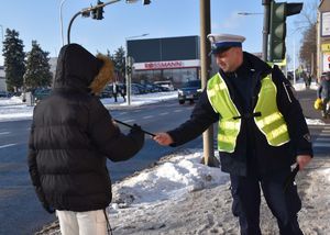 policjant podaje opaskę odblaskowa chłopcu