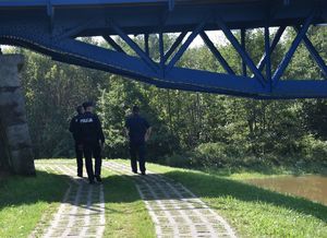 policjanci idą wzdłuż wału przeciwpowodziowego