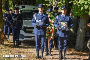 Policjanci niosą zdjęcie i czapkę służbową zmarłego policjanta.