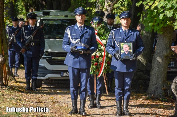 Policjanci niosą zdjęcie i czapkę służbową zmarłego policjanta.