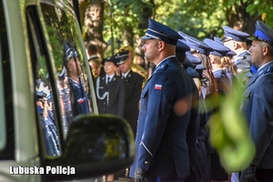 Policjant przy pojeździe na pogrzebie zmarłego policjanta.